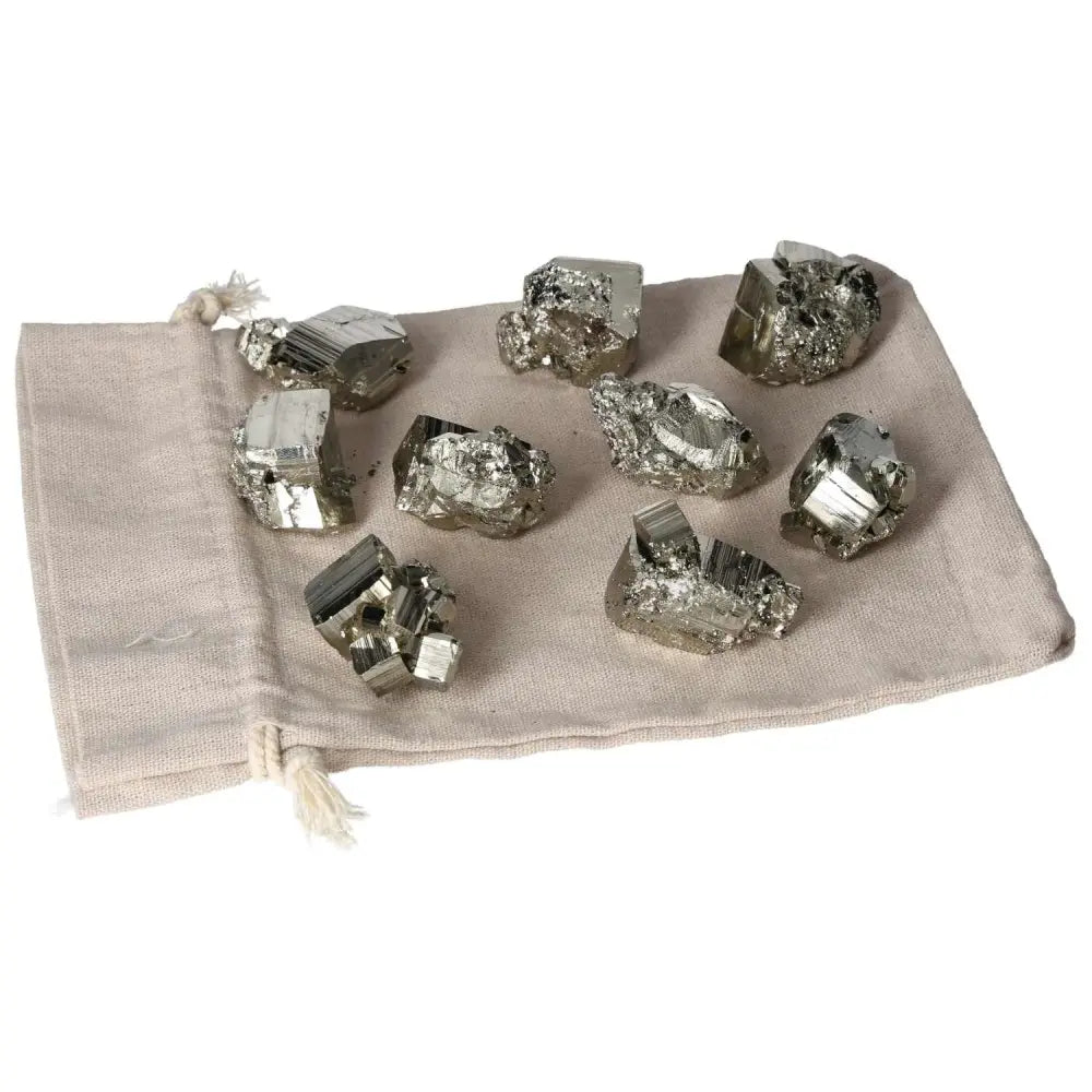 Collection of polished pyrite cubes displaying golden luster on a beige cloth, showcasing radiant energy and elegant design.