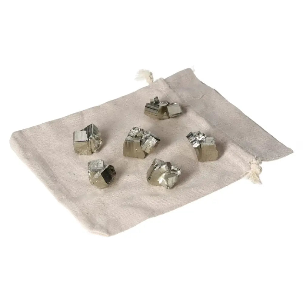 Assorted polished pyrite cubes on a beige cloth, showcasing their golden luster and grounding energy.
