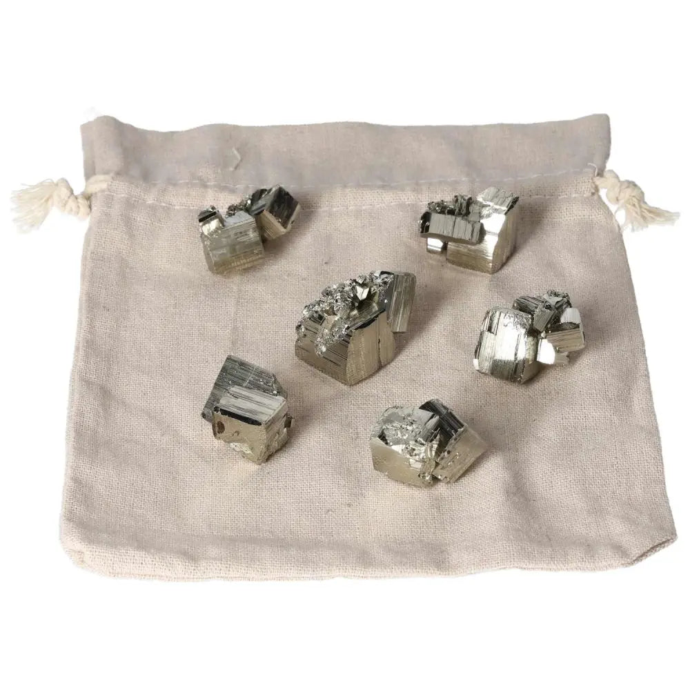 Six polished pyrite cubes displayed on a cloth bag showcasing their golden luster and grounding energy, ideal for spiritual spaces.