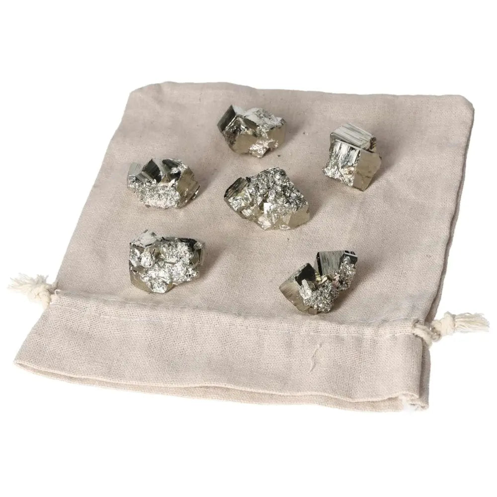 Assorted polished pyrite cubes displayed on a beige cloth bag, showcasing their golden metallic luster for energy grounding and decor.