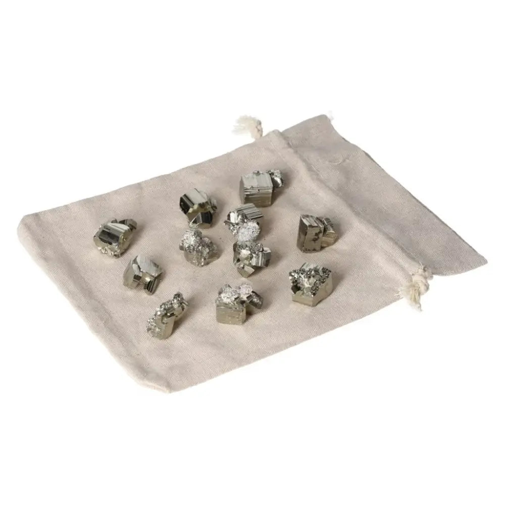 Polished pyrite cubes on a beige cloth bag, showcasing their golden luster and grounding energy.