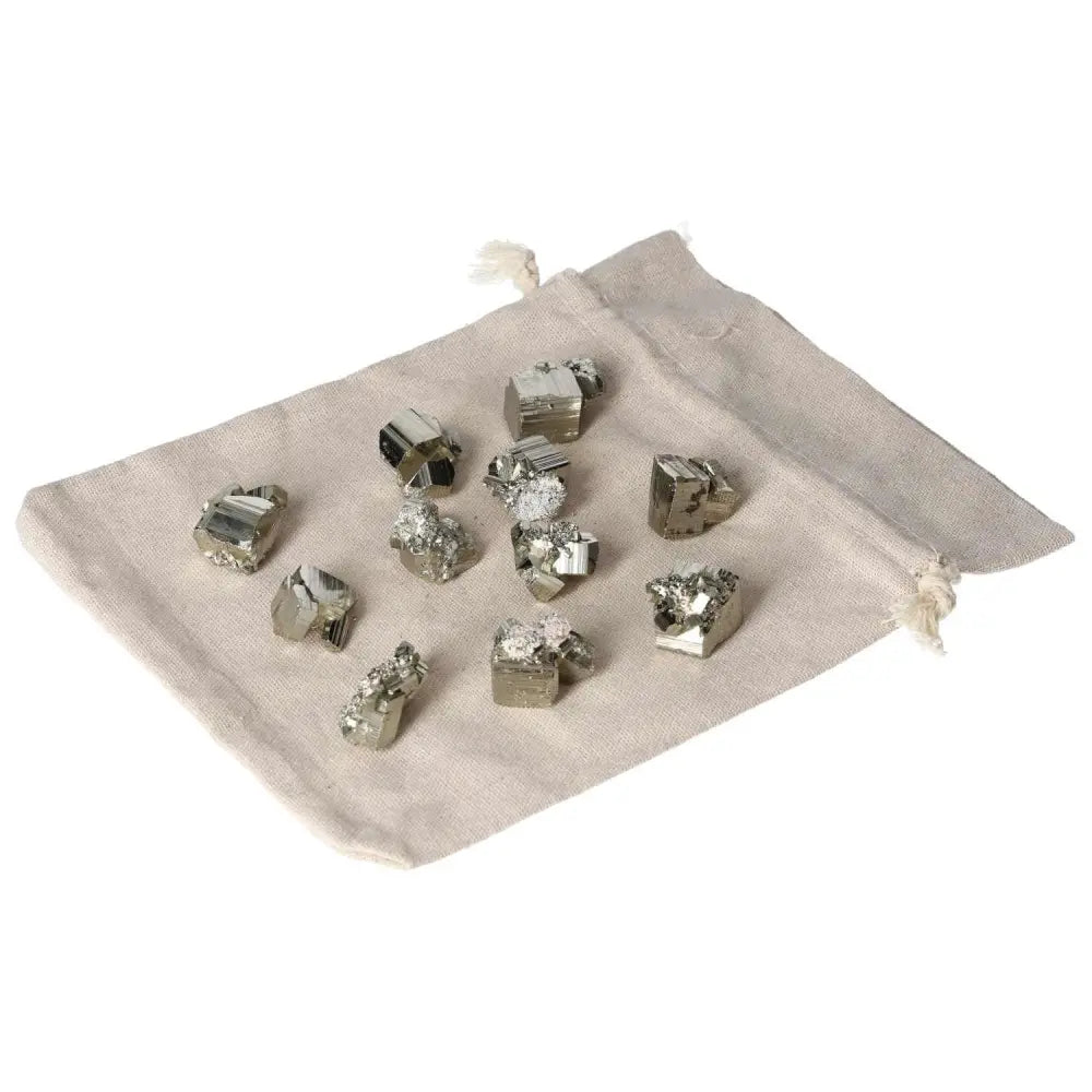 Collection of polished pyrite cubes on a beige fabric pouch highlighting the stone's golden luster and grounding energy.