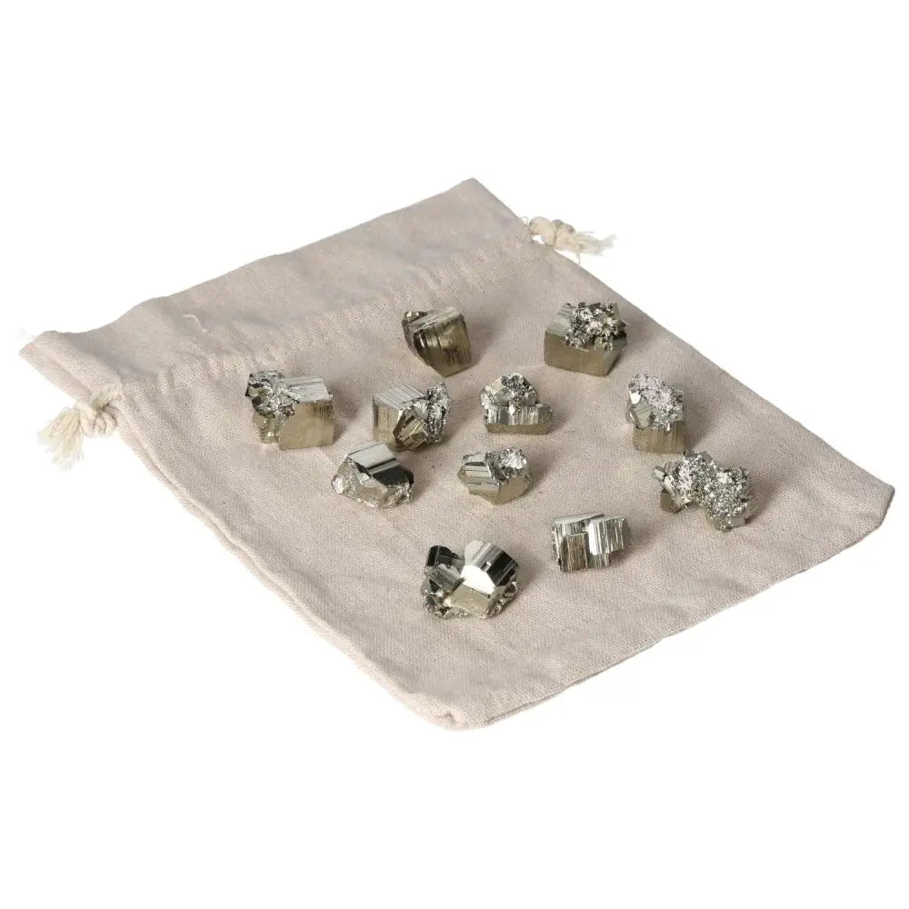 Small polished pyrite cubes displayed on a beige cloth, showcasing their golden luster and grounding energy for home decor or energy healing.