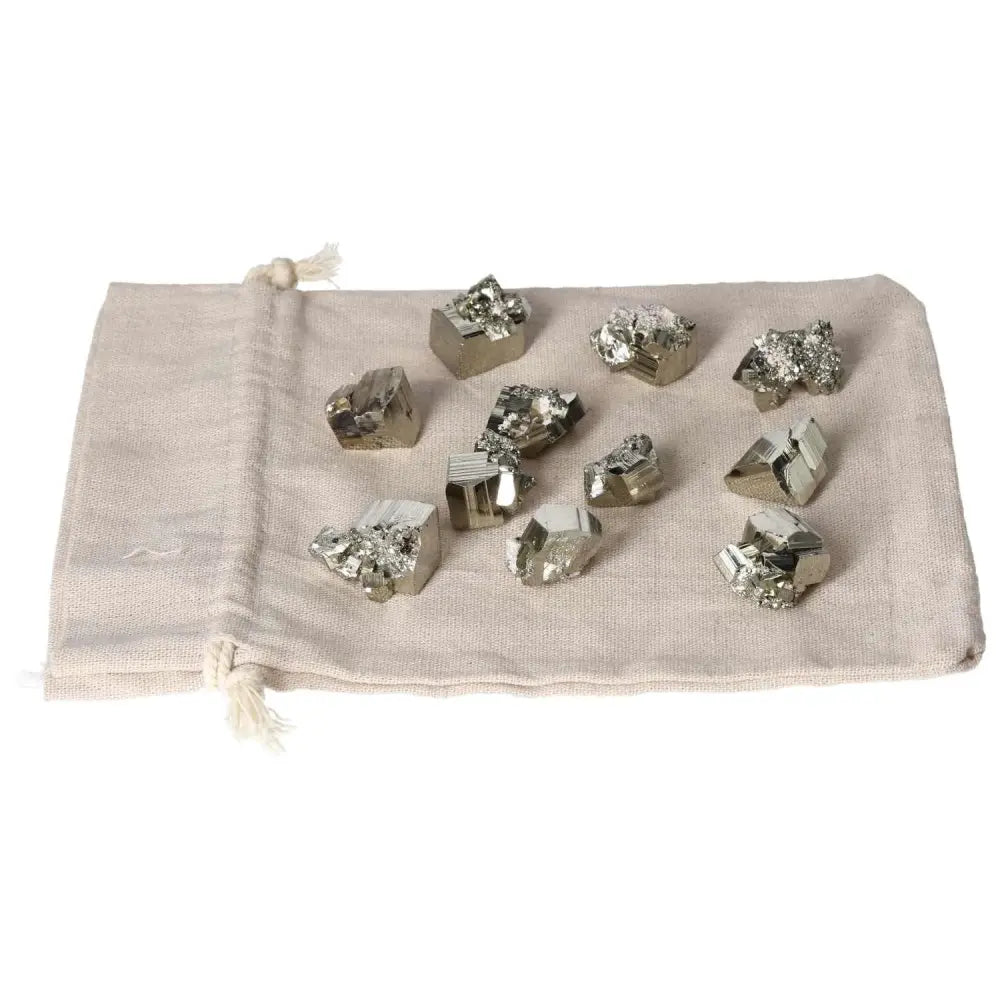Collection of polished pyrite cubes and hearts on a fabric pouch, showcasing natural golden luster and grounding energy properties.