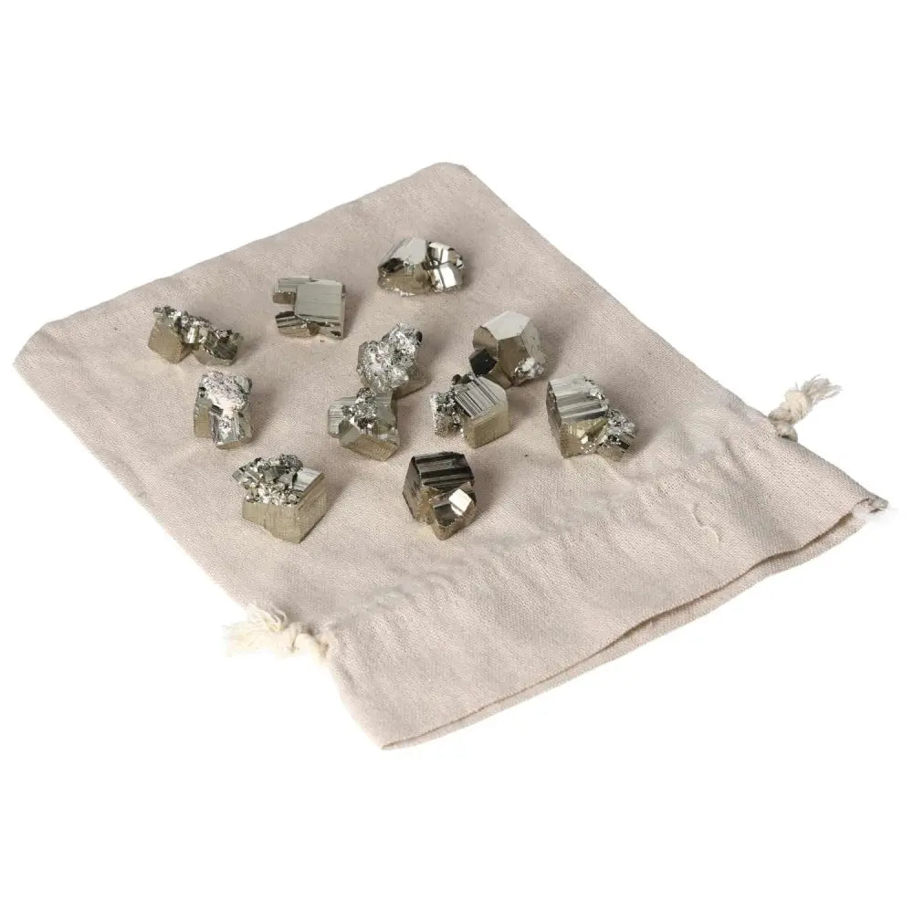 Assorted polished pyrite cubes on a drawstring cloth bag, showcasing metallic luster and geometric shapes.