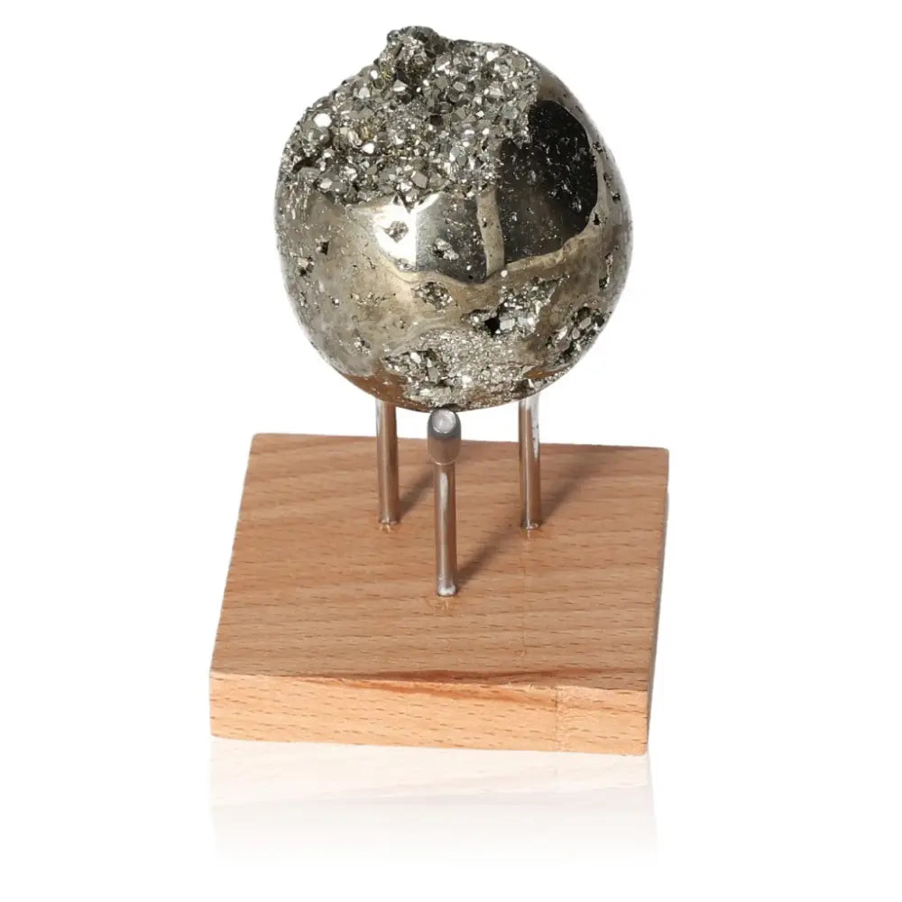 Shimmering Pyrite Egg on wooden stand, showcasing its metallic luster and golden hue, symbolizing abundance and prosperity.