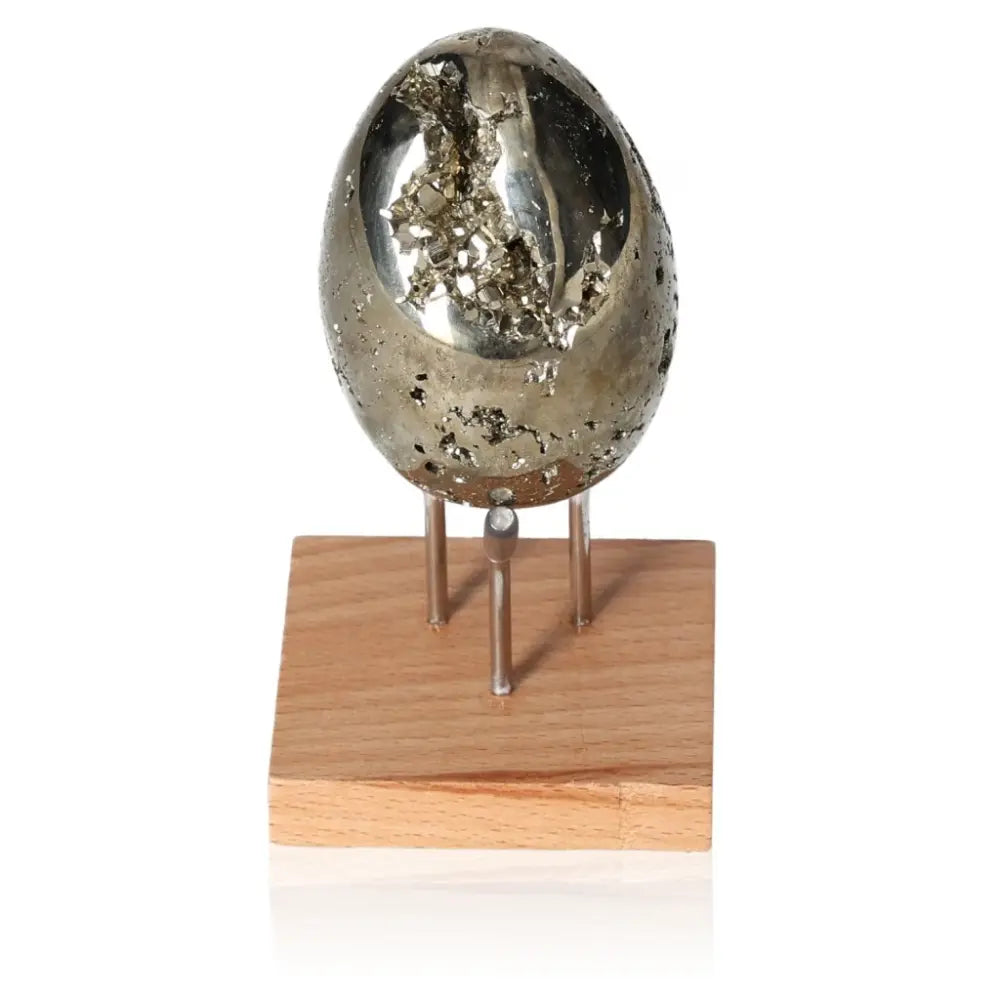 Alt Tag: Pyrite egg with metallic luster on wooden stand, symbolizing wealth and prosperity.