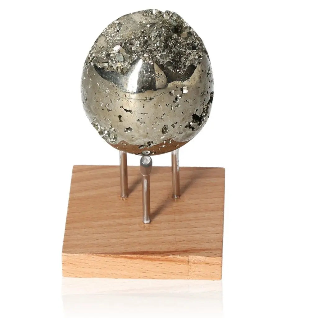 Radiant metallic pyrite egg on a wooden stand, known as "Fool's Gold," symbolizing abundance and prosperity.