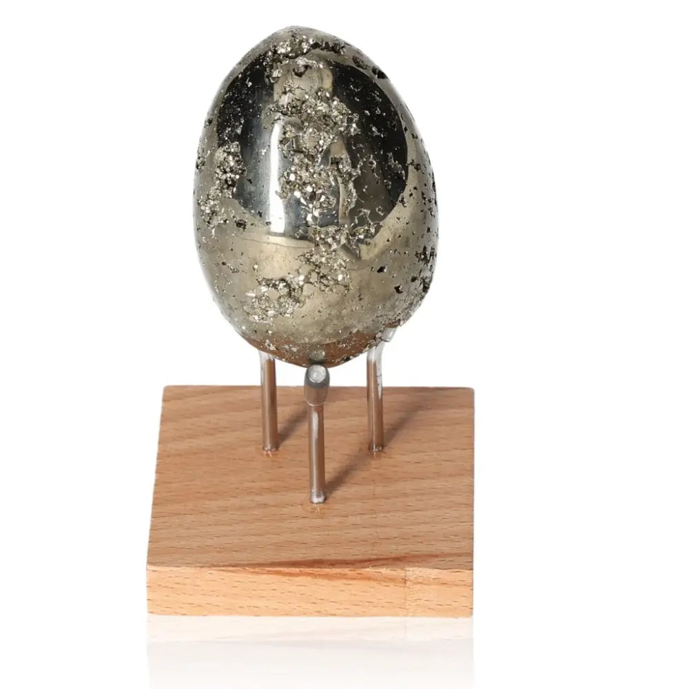 Pyrite egg sculpture with radiant golden hue on wooden stand, symbolizes wealth and prosperity, also known as Fool's Gold.
