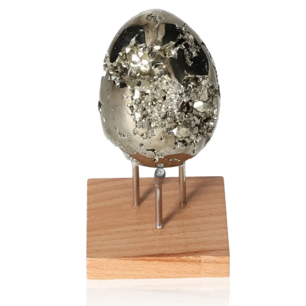 Pyrite egg with metallic luster on wooden stand, symbolizing abundance and prosperity.