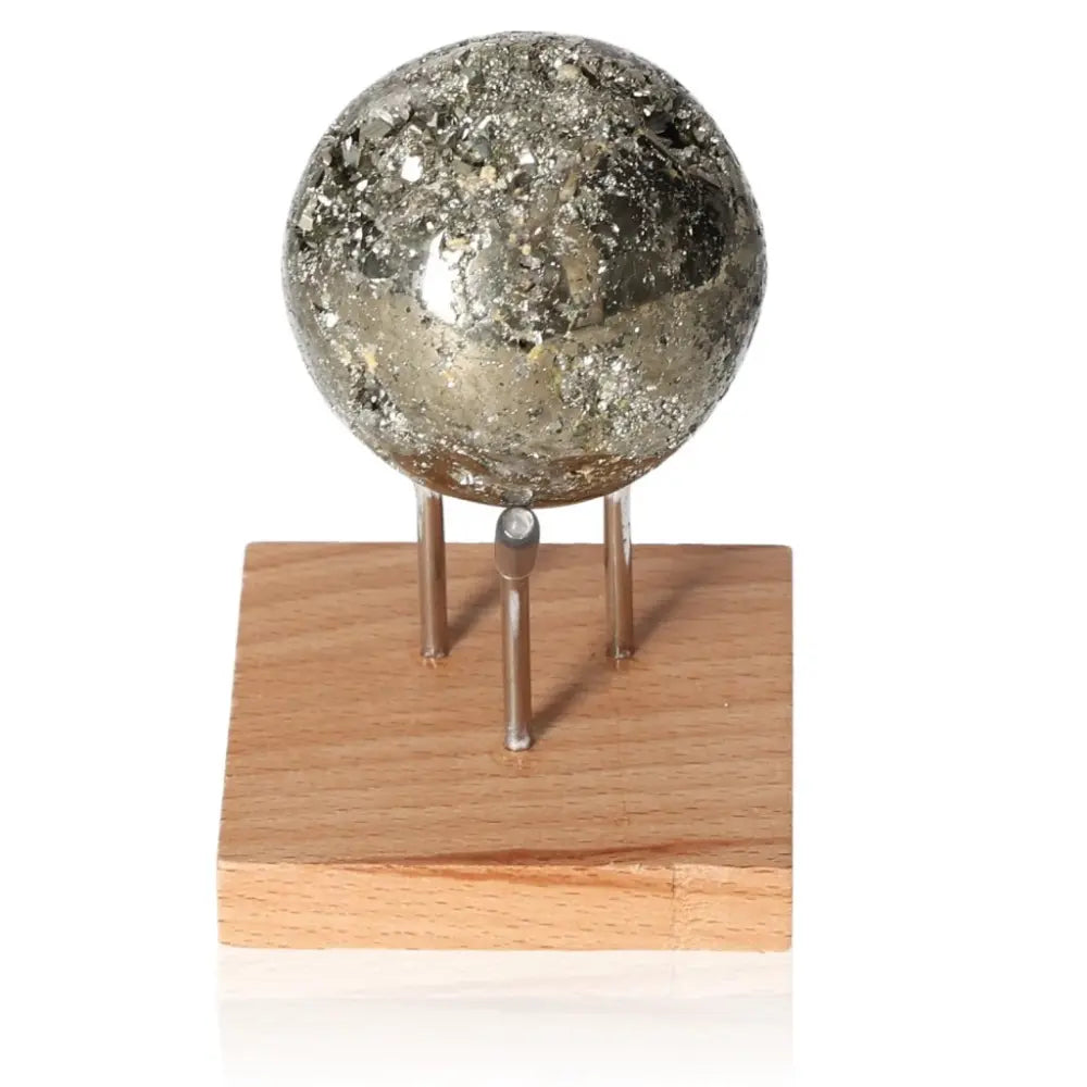 Pyrite sphere on wooden stand, shiny metallic mineral known as Fool's Gold, symbolizing abundance and prosperity.
