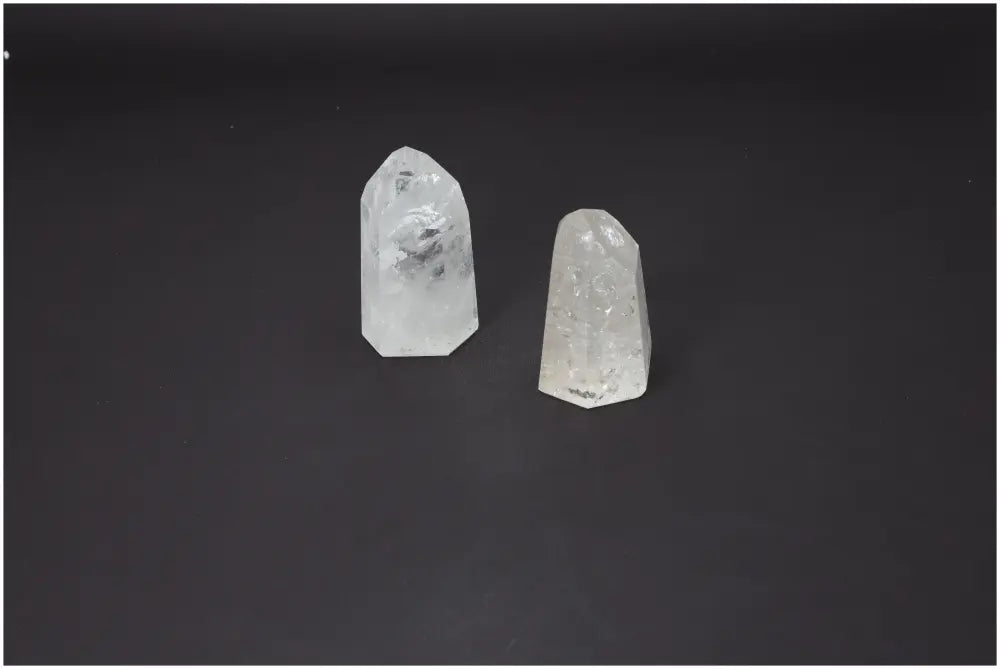 Two clear quartz obelisks weighing 1 kg each, known for purification and harmonizing energy, against a dark background.