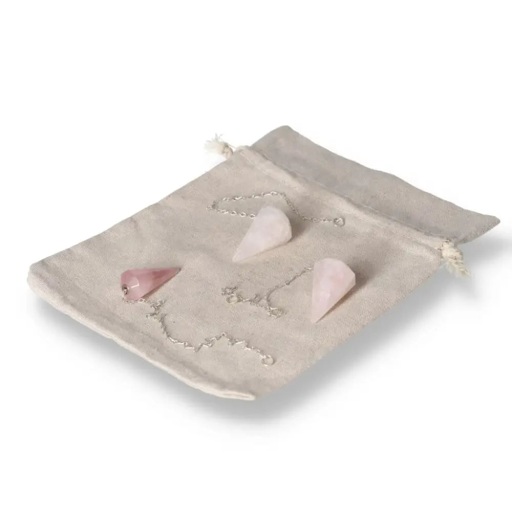 Rose Quartz pendulums on beige pouch, used for healing and enhancing love, trust, and emotional sensitivity.