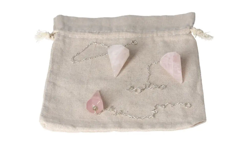 Rose Quartz pendulums set laid on a beige linen pouch, symbolizing love and emotional healing benefits.