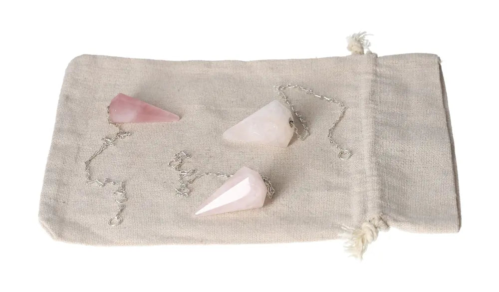 Rose Quartz pendulum set with silver chains on a beige fabric pouch, symbolizing love and emotional healing.