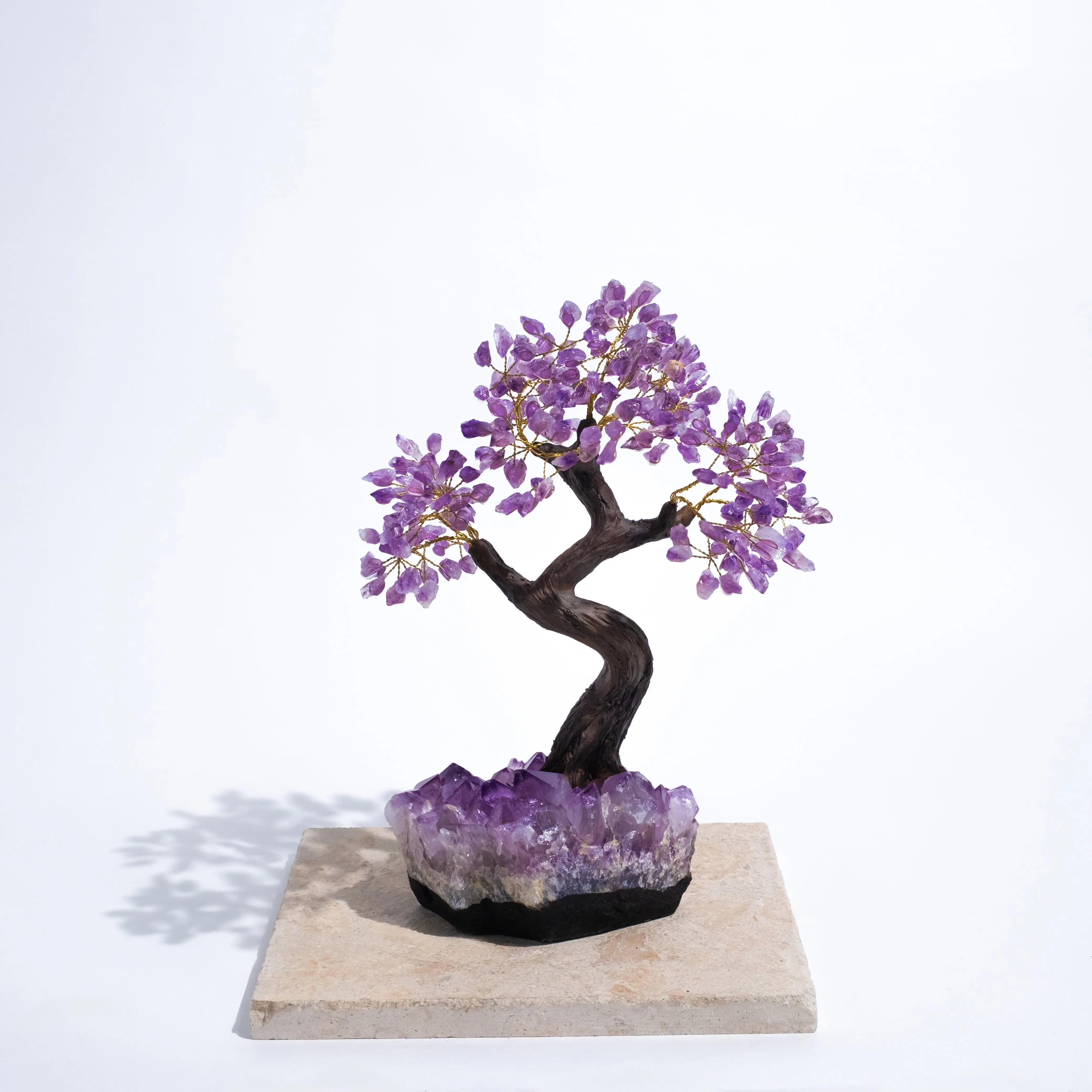 Rough amethyst crystal bonsai tree on stone base, promoting calming energy and spiritual harmony with purple gemstone leaves.