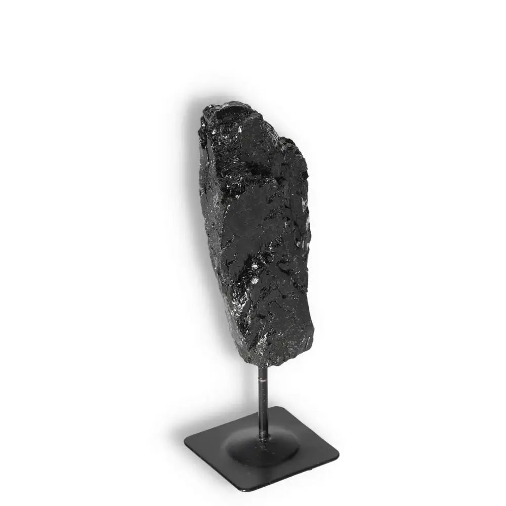 Black Tourmaline crystal on metal stand from Sylvia Crystals, known for cleansing negative energies.