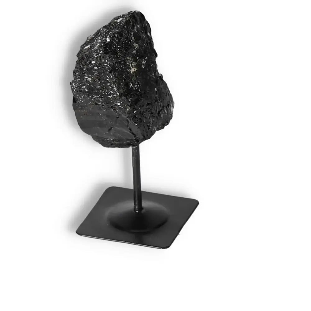 Rough black tourmaline on a sleek metal stand, exuding luxury and spiritual cleansing properties from Sylvia Crystals.