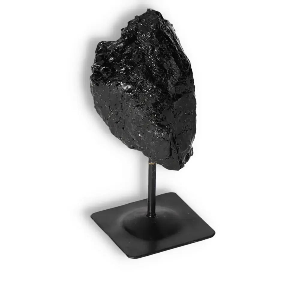Rough Black Tourmaline on metal stand, crafted by Sylvia Crystals, for energy cleansing and transformation, promoting balance and serenity.