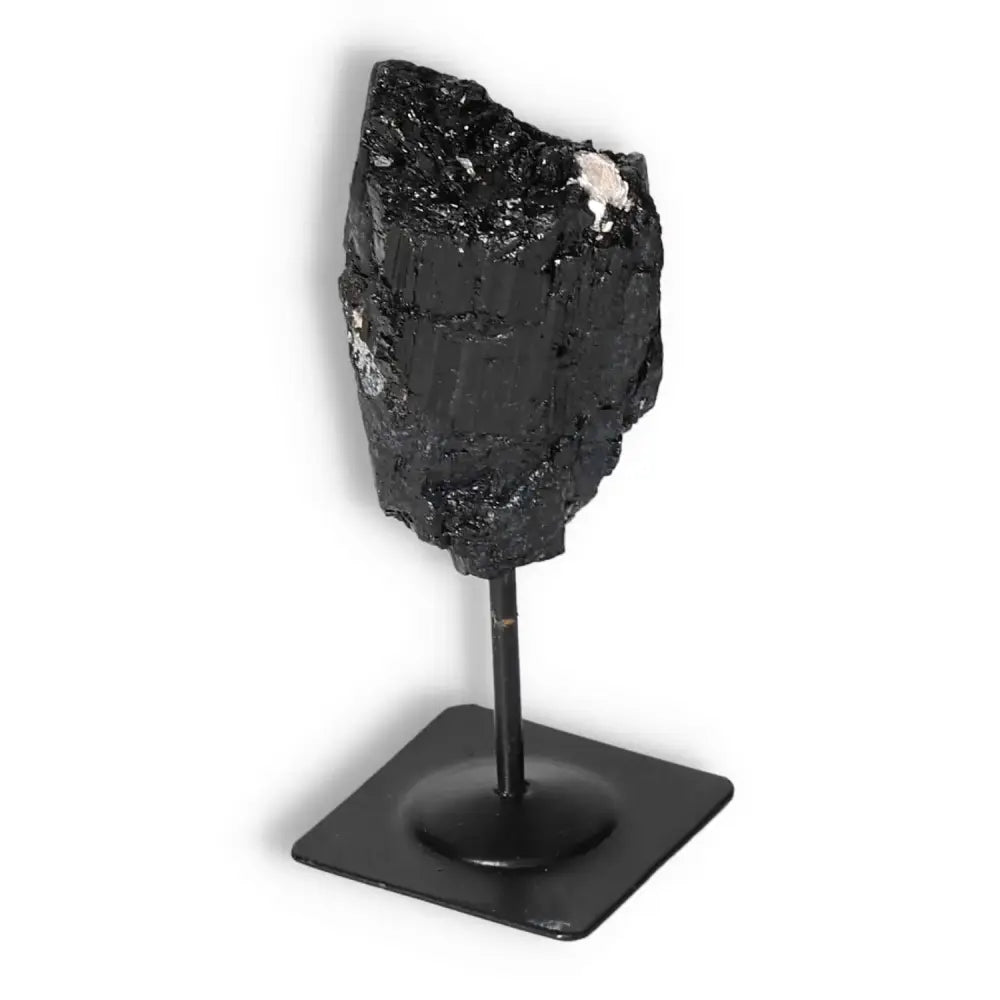 Premium Rough Black Tourmaline on metal stand by Sylvia Crystals for cleansing and balance, shown against a white background.
