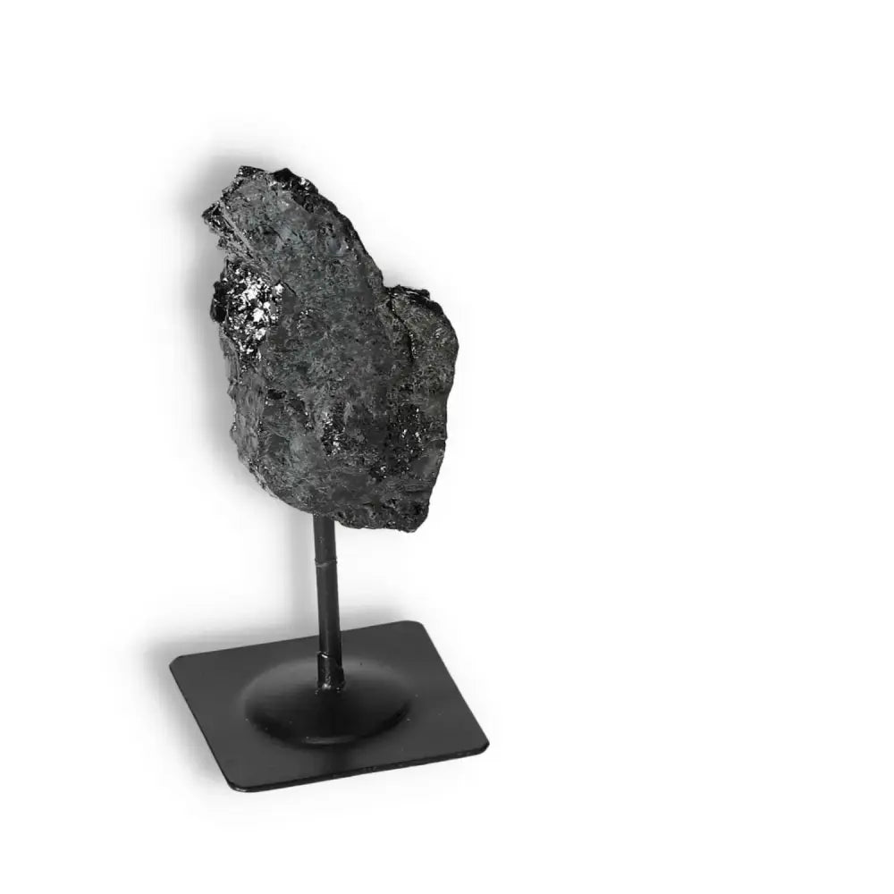 Rough Black Tourmaline on metal stand by Sylvia Crystals, a spiritual tool for cleansing negative energies, enhancing home decor.