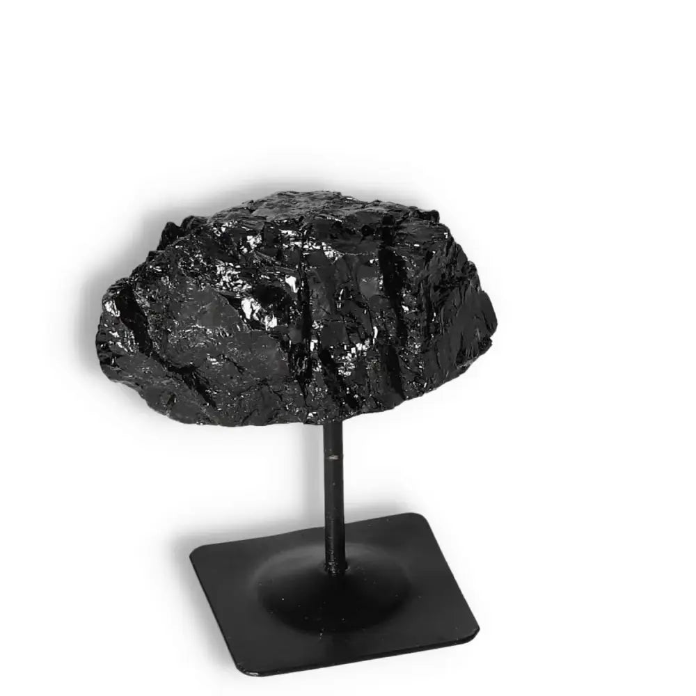 Rough Black Tourmaline on metal stand by Sylvia Crystals, known for spiritual energy cleansing and transformation.
