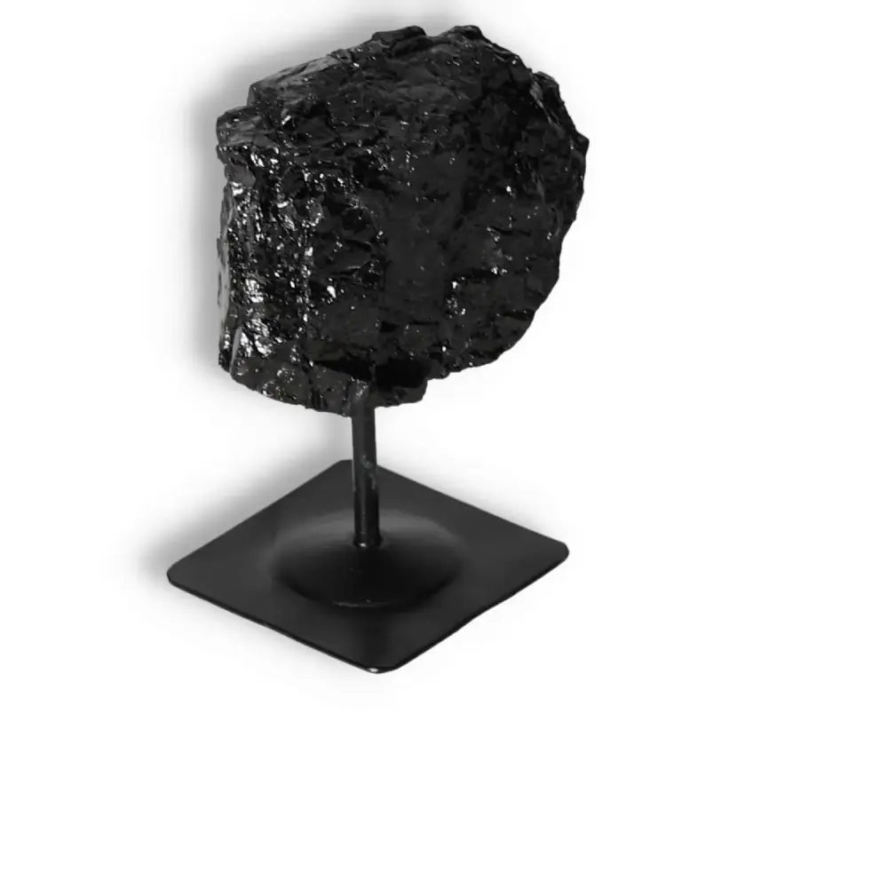 Rough black tourmaline on metal stand, enhancing spaces and transforming negative energies, by Sylvia Crystals. Ideal for spiritual benefits.