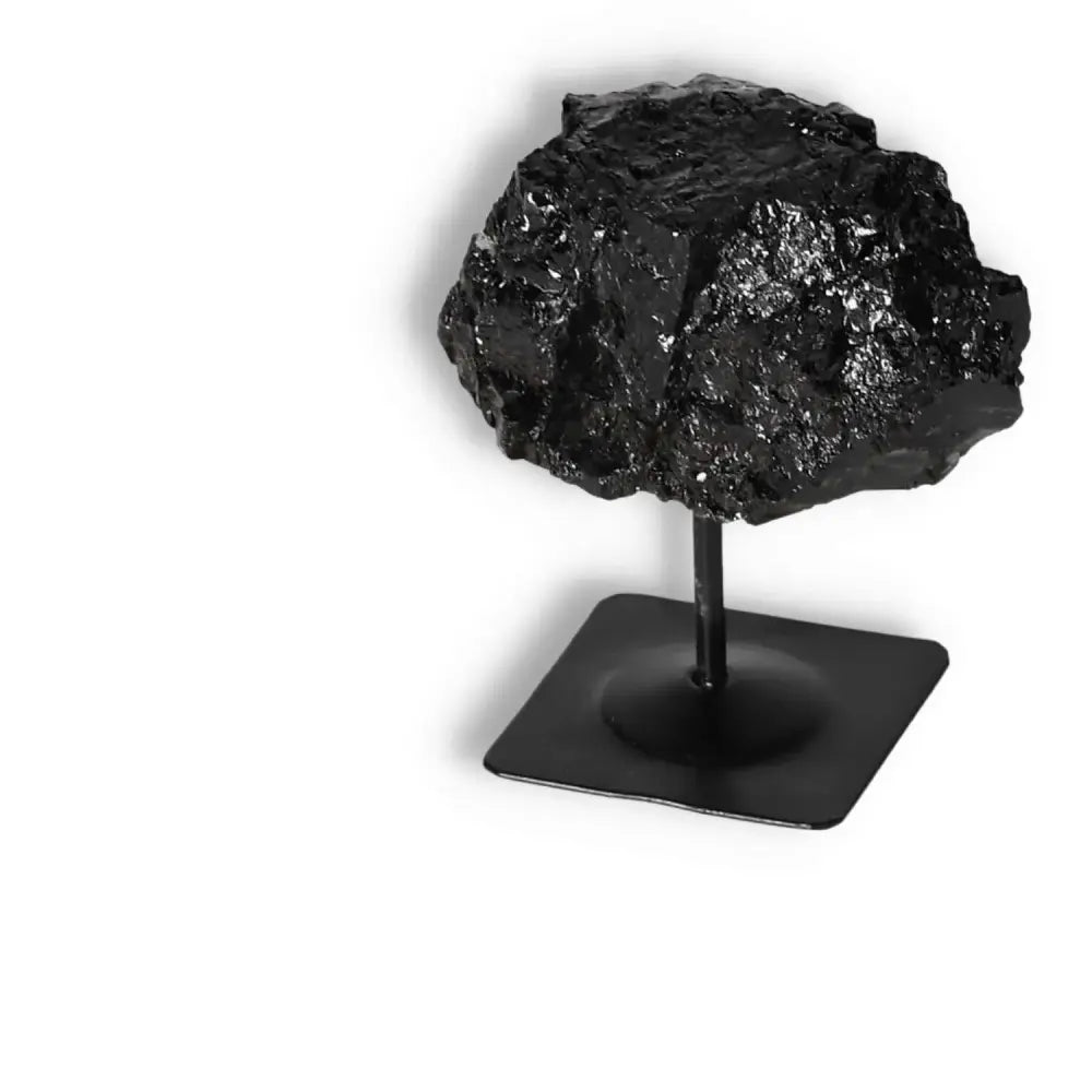 Rough Black Tourmaline on metal stand, Sylvia Crystals, known for cleansing negative energies and enhancing spiritual spaces.