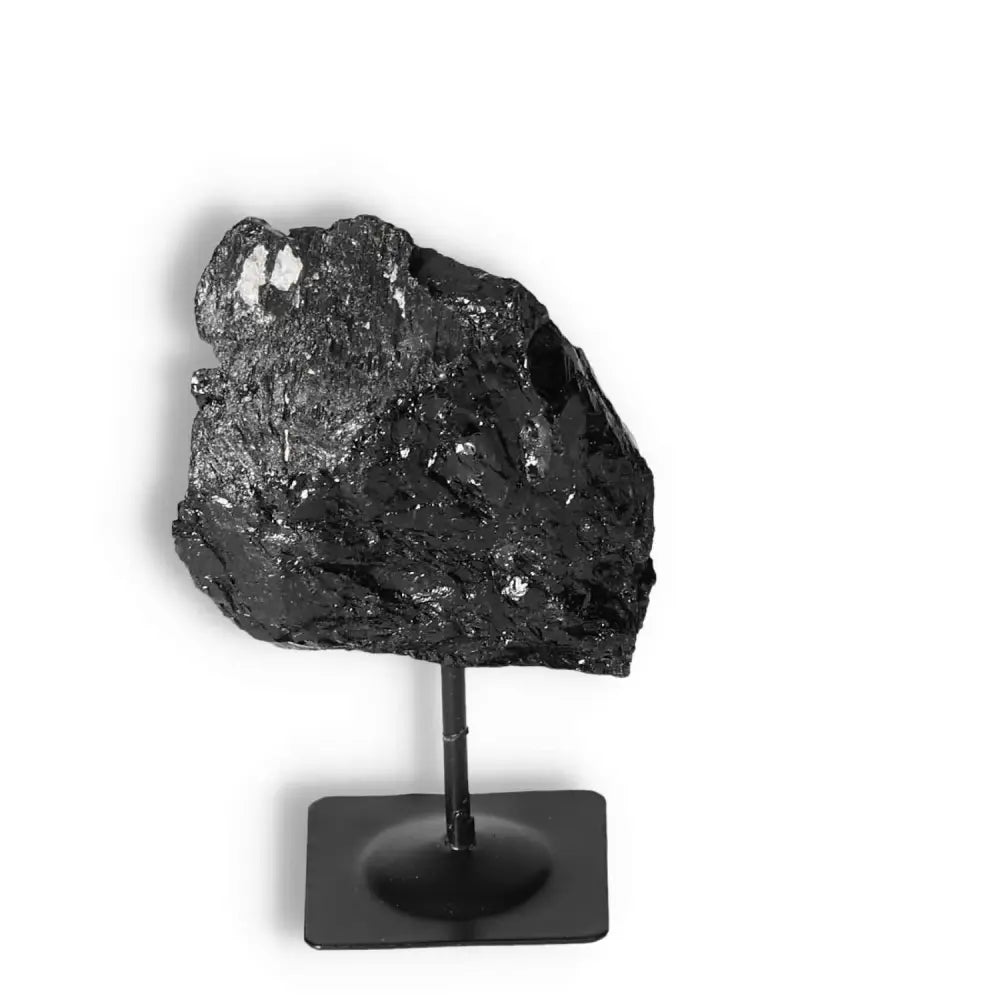 Rough black tourmaline crystal on a metal stand, enhancing home decor and promoting negative energy neutralization and mental stability.