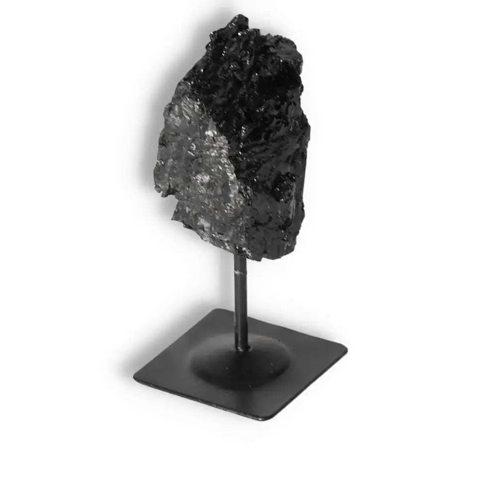 Rough Black Tourmaline crystal on metal stand, handcrafted by Sylvia Crystals, known for energy cleansing and authenticity.