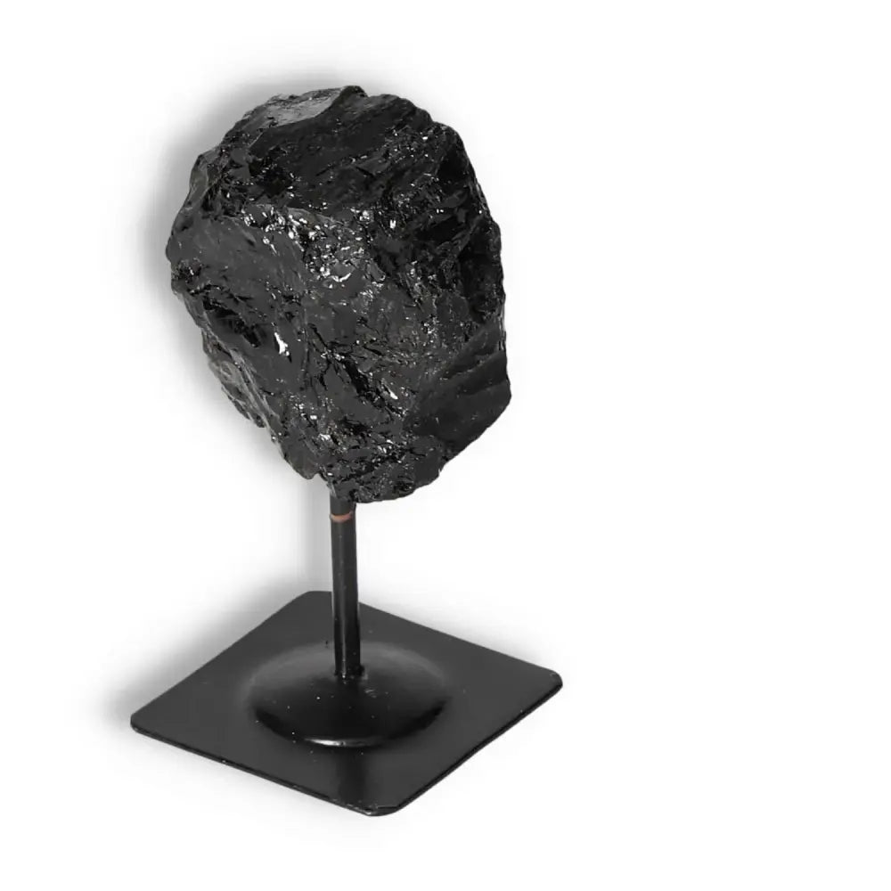 Rough Black Tourmaline gemstone on metal stand for energy cleansing and spiritual enhancement, from Sylvia Crystals.