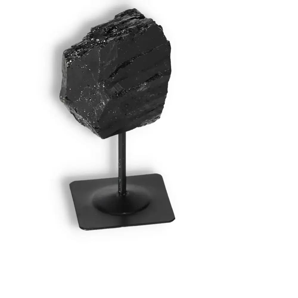 Rough Black Tourmaline on a metal stand by Sylvia Crystals, used for spiritual healing and negative energy cleansing.