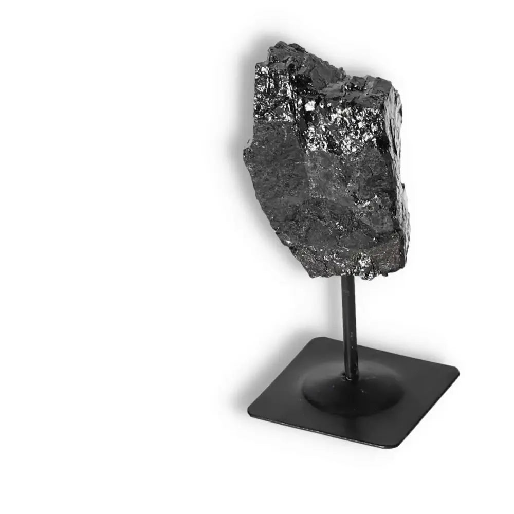 Rough Black Tourmaline crystal on a sleek metal stand for home decor and spiritual healing by Sylvia Crystals. Premium quality gemstone.