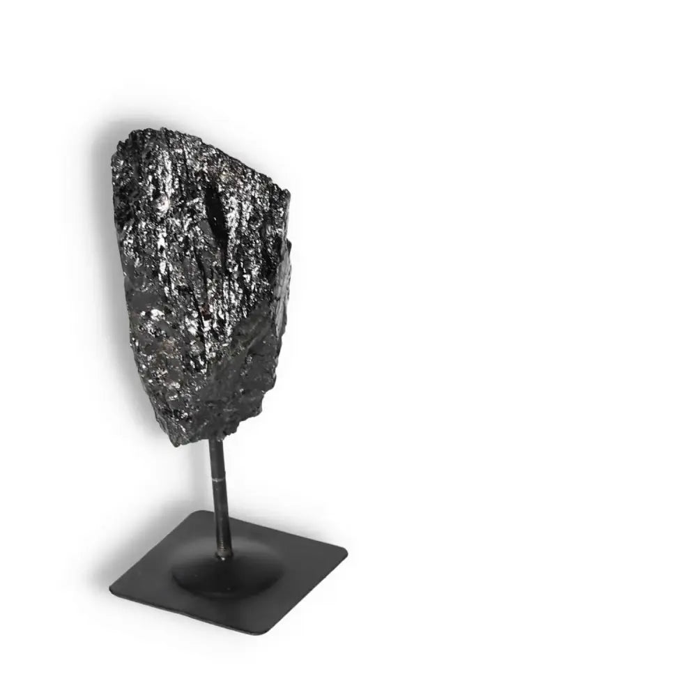 Rough Black Tourmaline on metal stand from Sylvia Crystals, showcasing cleansing and grounding properties. Elegant and mystical decor.