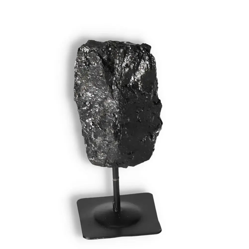 Rough Black Tourmaline on metal stand, showcasing its cleansing and grounding properties, ideal for mental balance and root chakra support.