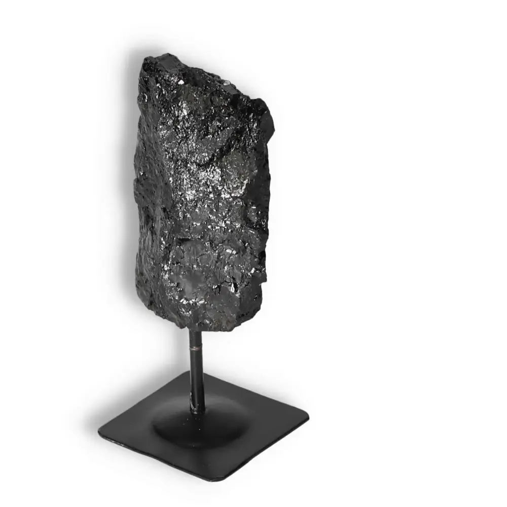 Rough Black Tourmaline crystal on a metal stand by Sylvia Crystals, known for cleansing energy and enhancing concentration.