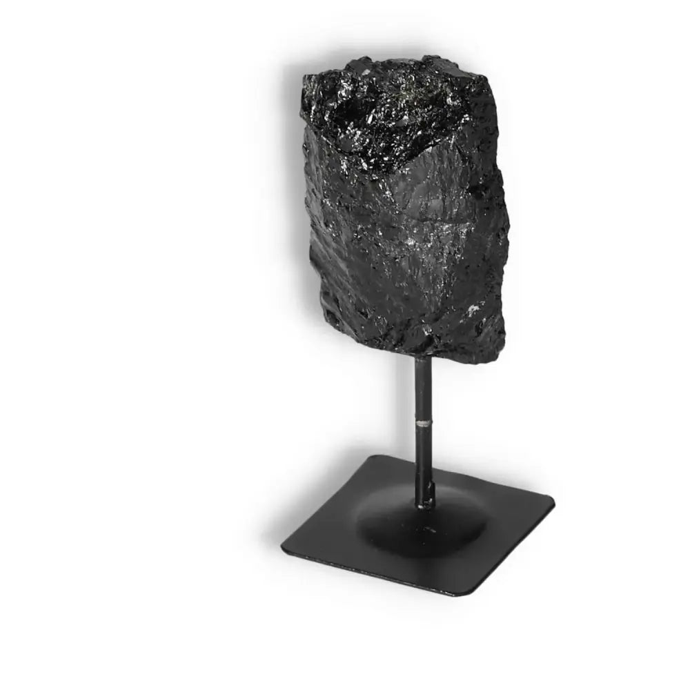 Rough Black Tourmaline on metal stand by Sylvia Crystals, known for dispelling negative energy and balancing the root chakra.