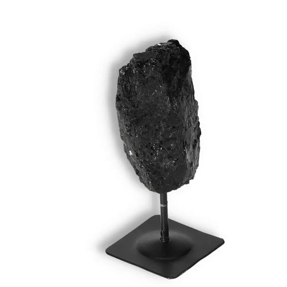 Rough Black Tourmaline with metal stand, showcasing cleansing energy and grounding properties, ideal for home decor and energy balance.