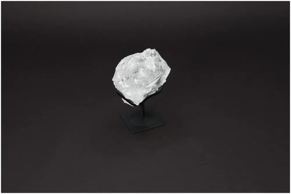 Rough Lemurian Quartz on metal stand, showcasing its clear crystalline formation against a dark background by Sylvia Crystals.