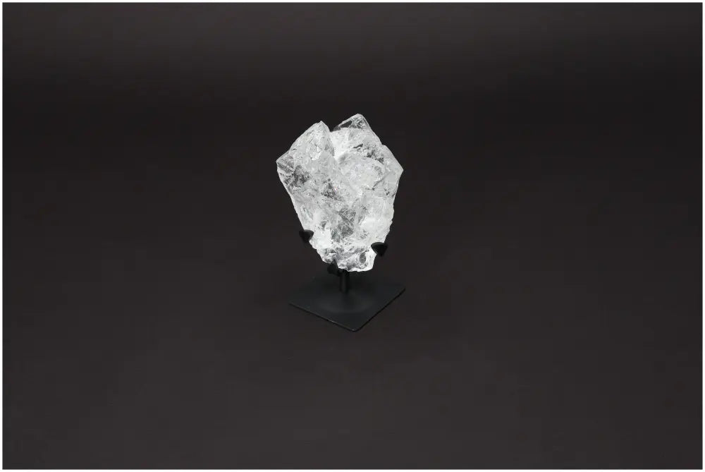 Rough Lemurian Quartz on metal stand by Sylvia Crystals, offering elegance and spiritual purity against a dark background.