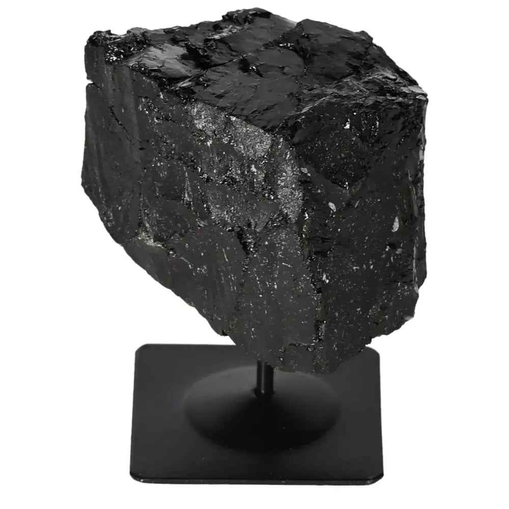 Rough tourmaline stone displayed on a metal stand, showcasing its raw black crystal texture.