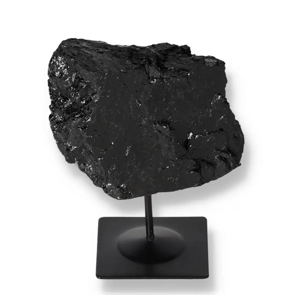 Elegant rough black tourmaline stone on a sleek metal stand, ideal for luxury home decor and energy balancing by Sylvia Crystals.