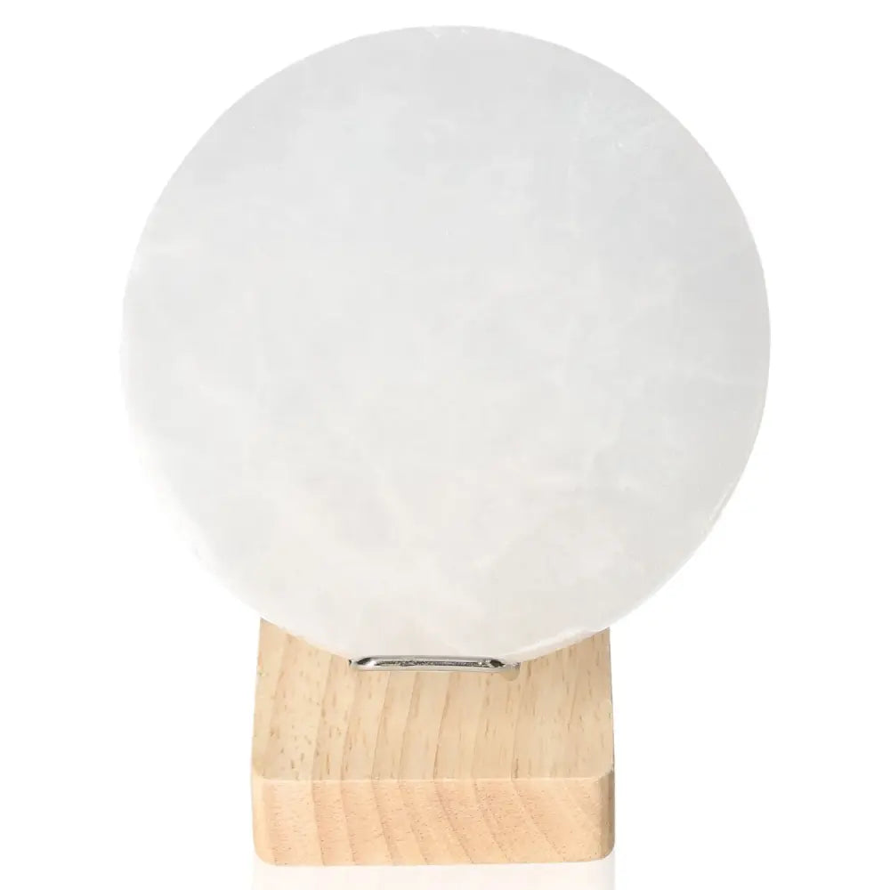 Selenite Disk 12cm by Sylvia Crystals, a premium-quality crystal for mindful living and spiritual growth, displayed on a wooden stand.