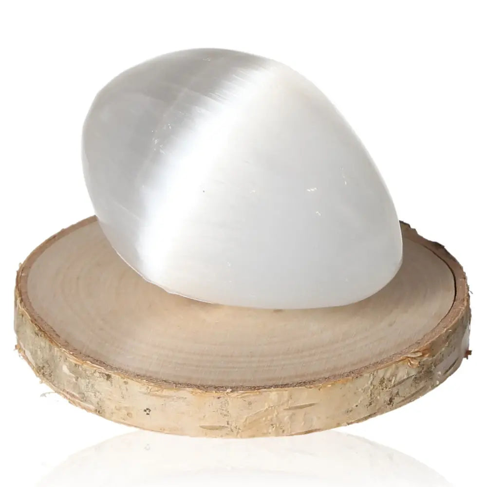 Selenite egg on wooden stand, showcasing its glass-like transparency and natural striations. Ideal for creating a soothing, harmonious space.