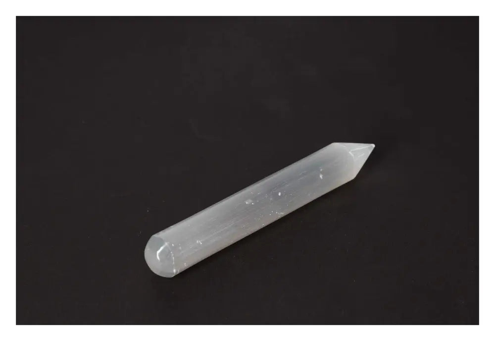Selenite massage wand with a silky, ethereal finish on a black background, ideal for enhancing calming and purifying atmospheres.