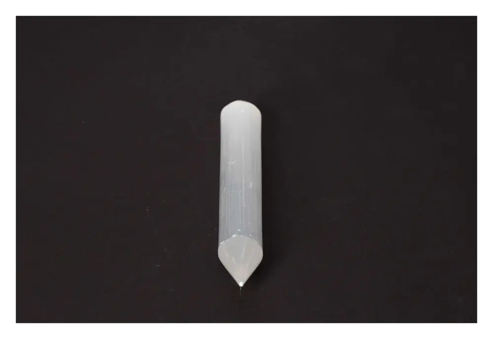 Elegant translucent selenite massage wand displayed on a dark background, highlighting its natural striations and ethereal glow.