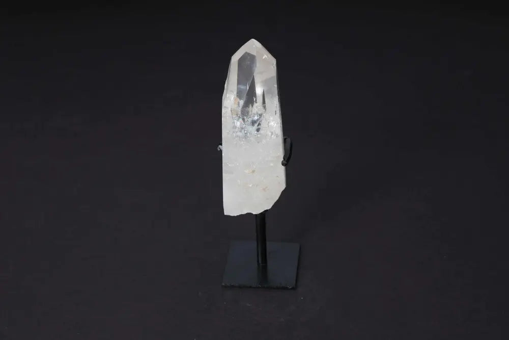 Semi Polished Clear Quartz Point on stand, ideal for meditation, energy work, enhancing clarity and intention, on a dark background.