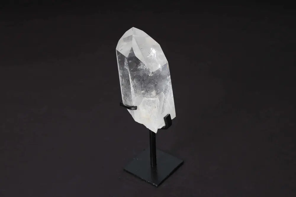 Semi-polished clear quartz point with stand, ideal for meditation and energy work, on elegant dark background.