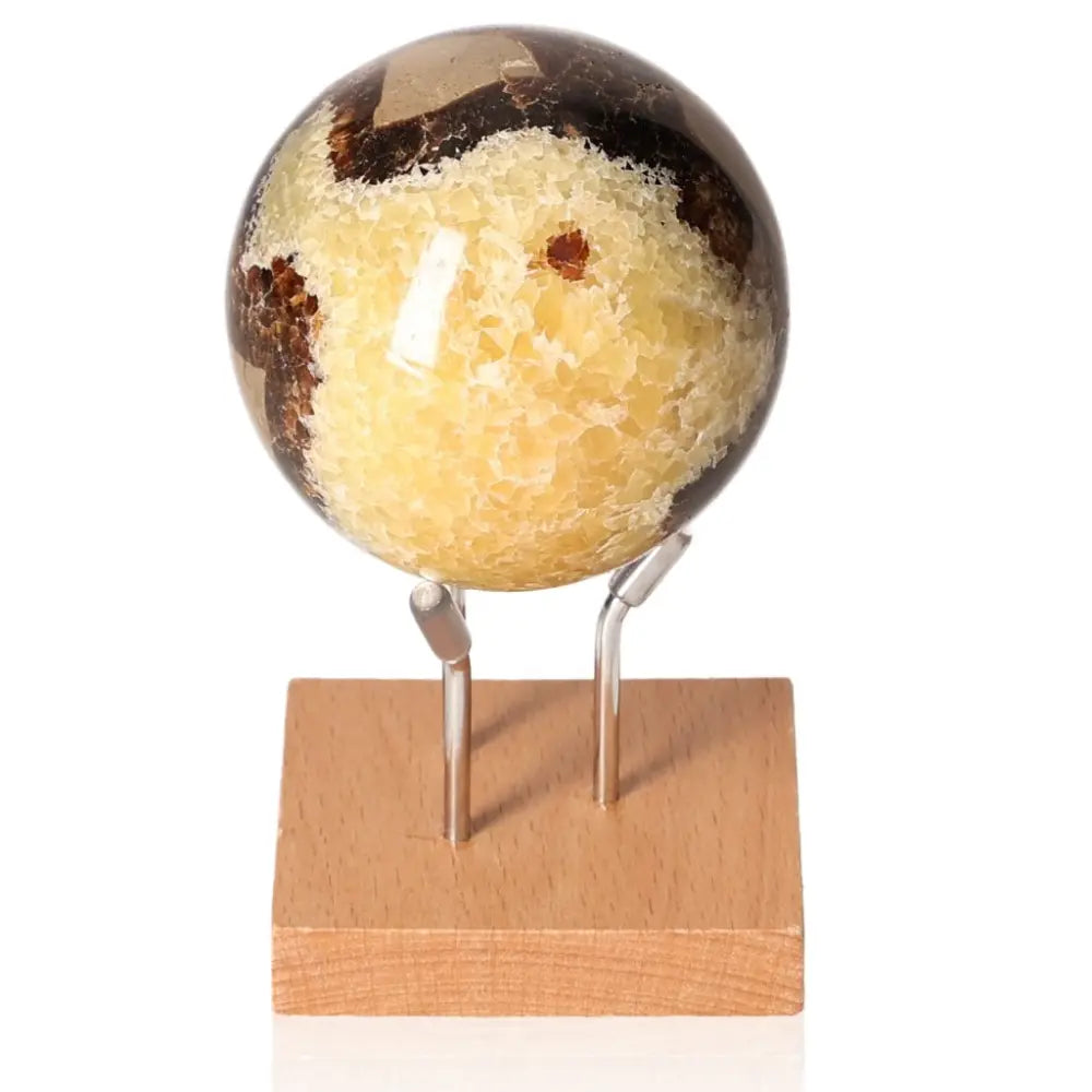 Septarian Sphere, also known as Dragon Stone, on a wooden stand displaying its unique mineral pattern and color variations.