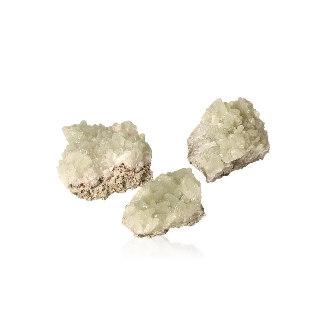 Small Prehnite druzy stones in pale green, known for their calming properties and spiritual growth enhancement.